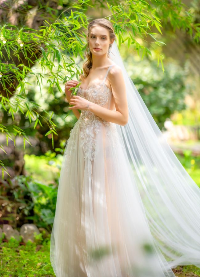 ethereal wedding dress woman besides leaves